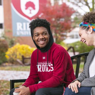 Students laugh and talk on bench