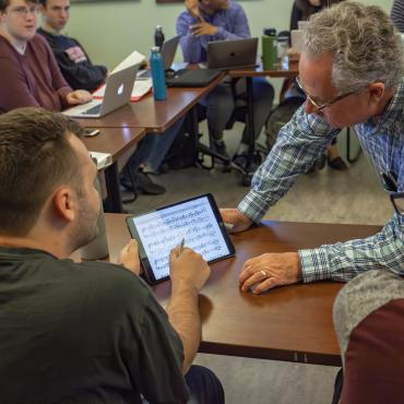 Male faculty member helps student on ipad