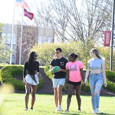 Four students walk across the campus mall
