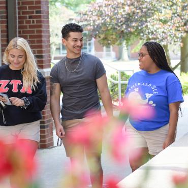 Three students walk across campus