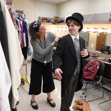Faculty member helps student backstage during performance
