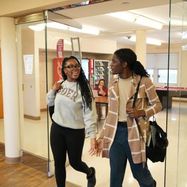 Two students walk through residence hall doorway