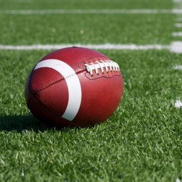 Football sits on green turf field