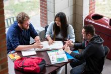 Students sit around a table studying.