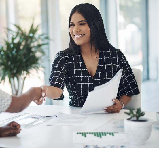 two young businesswomen shaking hands in a modern office stock photo