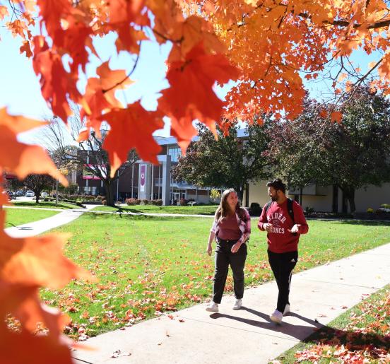 Two students walk on campus in fall