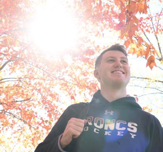 Student walks under fall leaves