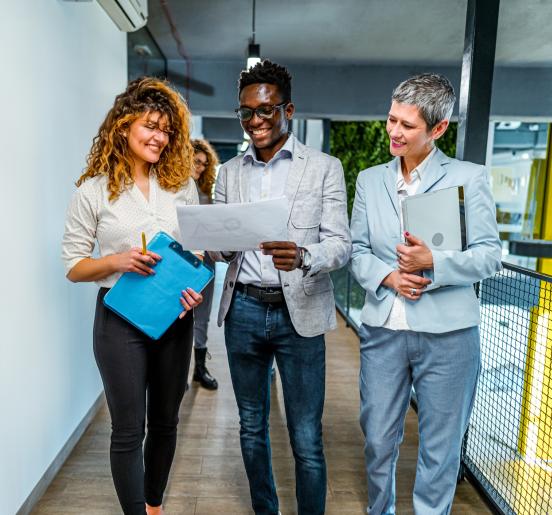 Smiling man and two women at work looking at a report together