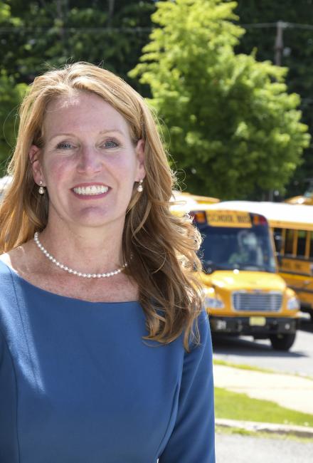 Kari McGann, Class of 2020 in front of school busses
